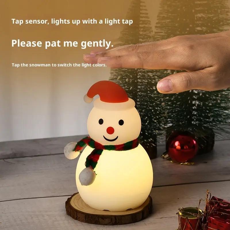 Snowman-shaped night light with a hand tapping it, surrounded by Christmas decorations.