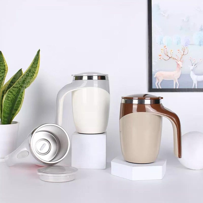 Set of ceramic mugs and a coffee press on a white surface with a plant and framed picture in the background.
