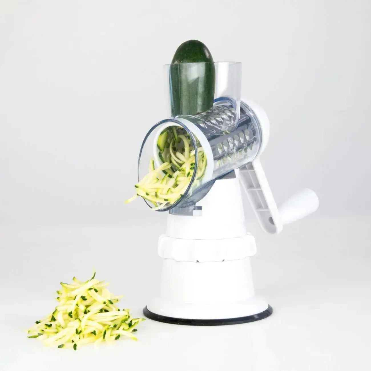 Manual spiralizer with zucchini being shredded on a white background