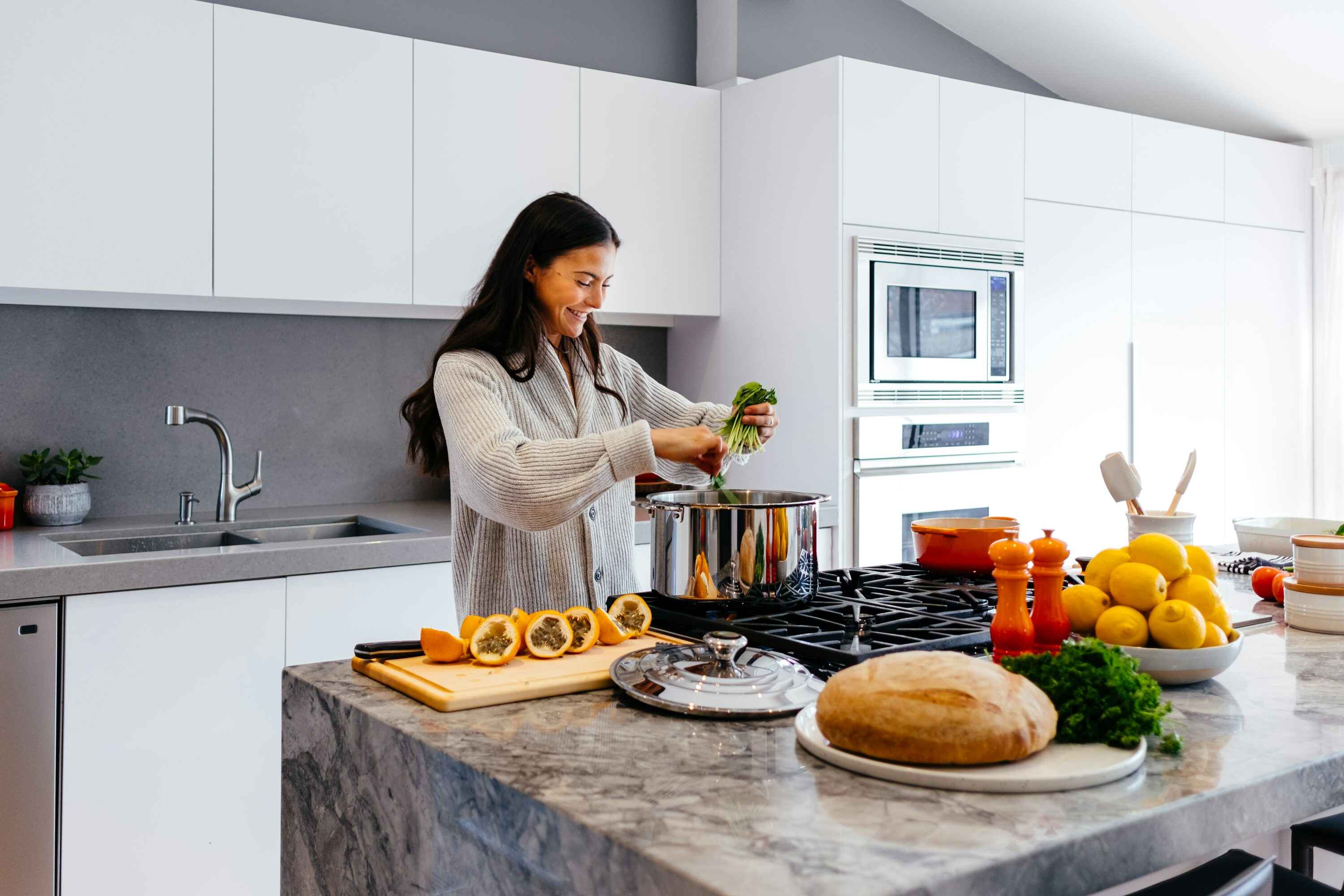 Woman cooking in a modern kitchen with various ingredients on the counter.